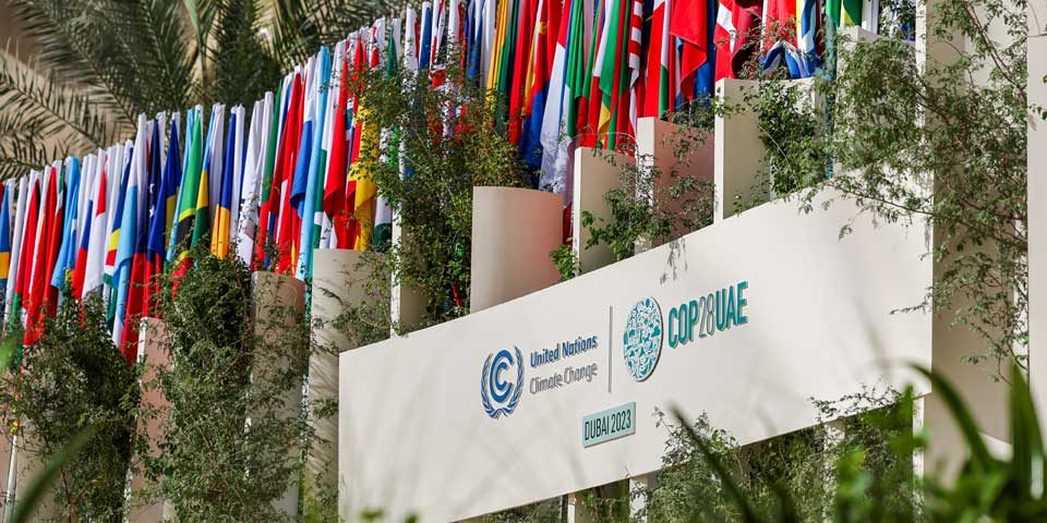 53365691971_c13d21f2c6_o_960 Flags from many countries hang above a sign for COP28 Dubai.