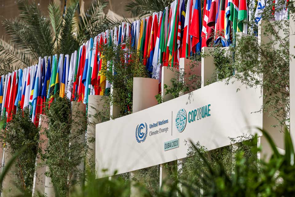 Flags from many countries hang above a sign for COP28 Dubai.