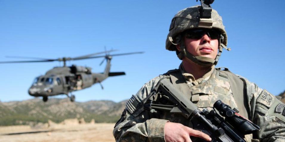 4452731297_71b0bcf011_o A US soldier in Afghanistan stands with agun, while a Blackhawk helicopter lands behind him.