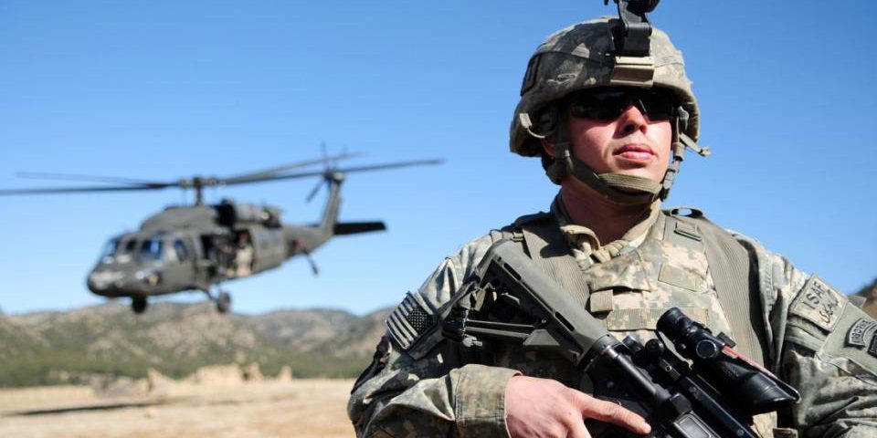 4452731297_71b0bcf011_o A US soldier in Afghanistan stands with agun, while a Blackhawk helicopter lands behind him.