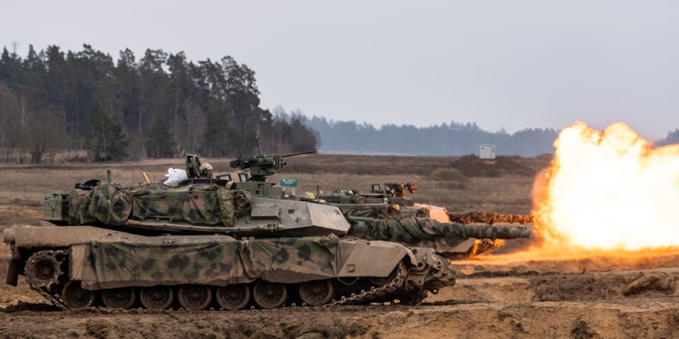 nato_livefire_960 Two Abrams tanks on a firing range fire producing large bursts of flame during a NATO exercise in 2024.