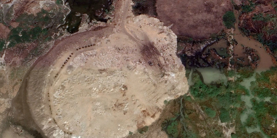 aden_dumpsite_960 The satellite image shows a circular mounded dump spreading over a wetland habitat and creeks.