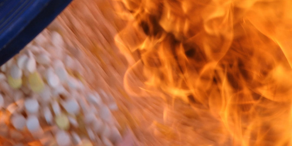 Burning_captagon_960 A blurred close up image shows white pills being consumed by orange flames.