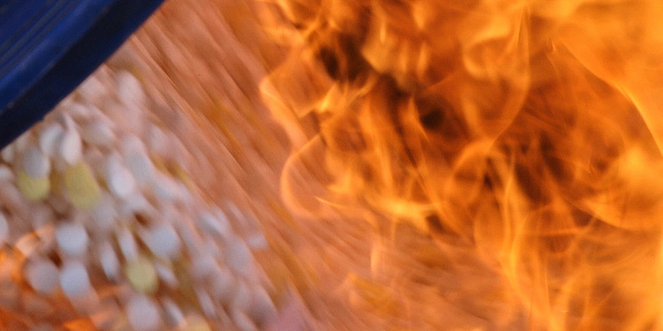 Burning_captagon_960 A blurred close up image shows white pills being consumed by orange flames.