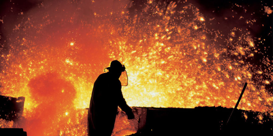 steel_foundry_960 Metallurgist working by the blast furnaces in Třinec Iron and Steel Works.. A man in protective clothing is silhouetted against orange and yellow sparks and glow from the furnace.