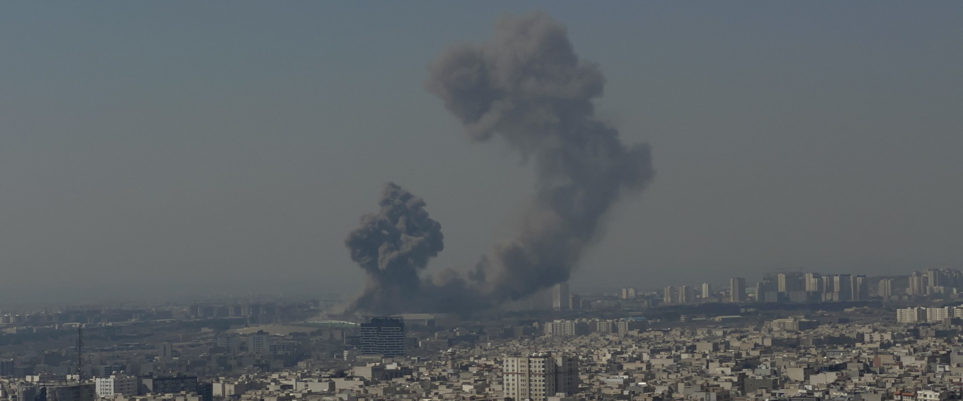 A large exposion and smoke plume visible in the Tehran skyline.