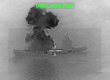 A grainy black and white image from the US military showing a black smoke plume rising above a small aircraft carrier at sea, titled with UNCLASSIFIED in green letters.