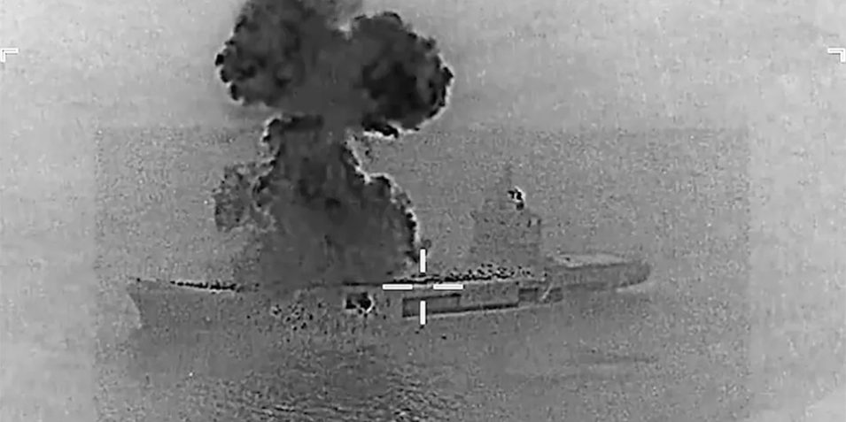 A grainy black and white image from the US military showing a black smoke plume rising above a small aircraft carrier at sea, titled with UNCLASSIFIED in green letters.