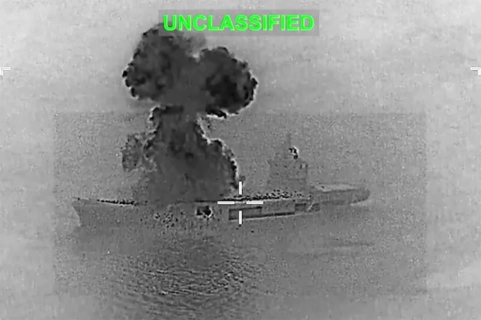 A grainy black and white image from the US military showing a black smoke plume rising above a small aircraft carrier at sea, titled with UNCLASSIFIED in green letters.