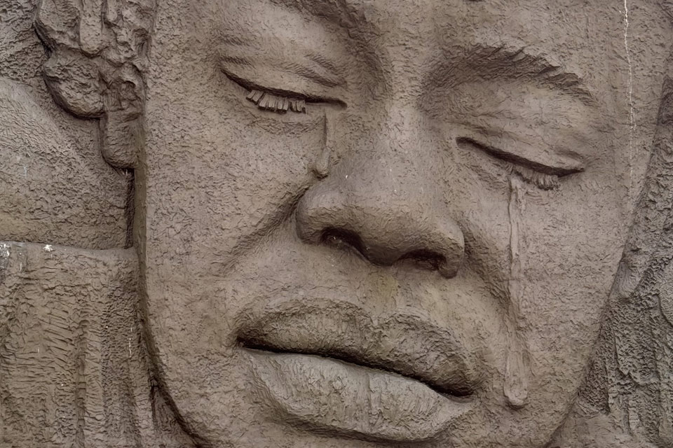 A close up of a bas relief sculpture of the crying face of an Angolan.