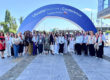 A group of around 30 manly female campaigners stand below an arch reading Ukraine Recovery Conference Gdansk Poland 2026.