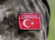 Close up of a badge on a soldier's mottled camouflage uniform, The red rectangle reads Turkiye and features the flag's crescent moon and star picked out in white embroidery.